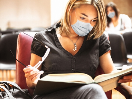 Student wearing protective COVID-19 mask as she studies.