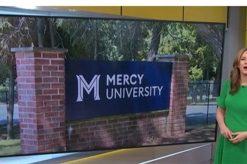 News 12 anchor with Mercy University sign in the background