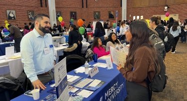 Mercy University student networks with staff and potential employers at 2024 Career Fair
