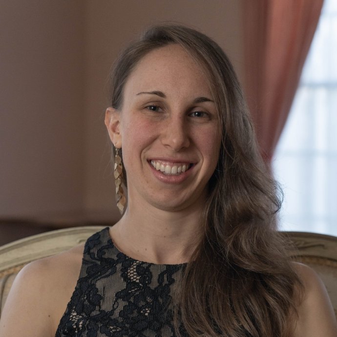 Shoulder-width photo of a white woman wearing a black dress and long brown hair