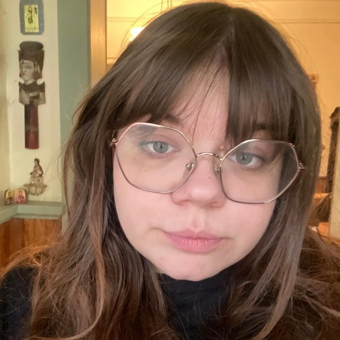 Picture of a young woman with brown hair and glasses. 