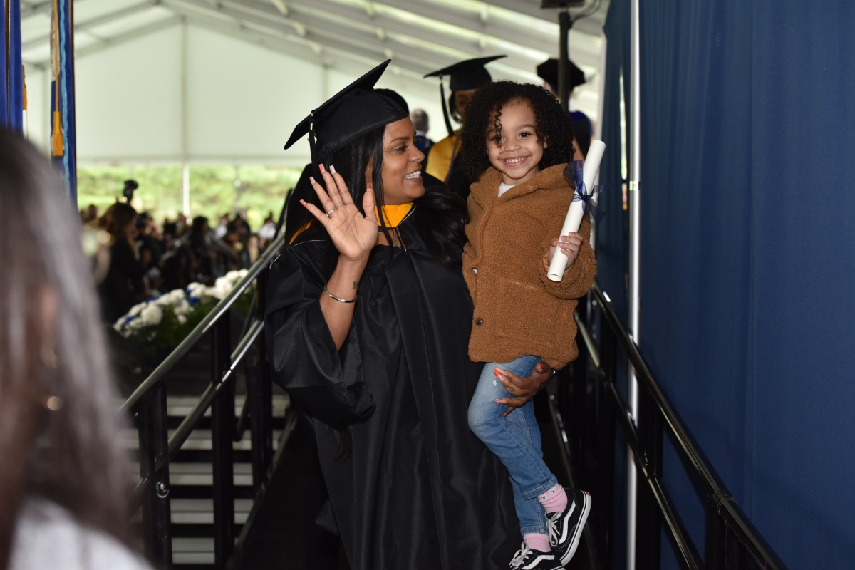 Student holding child at commencement