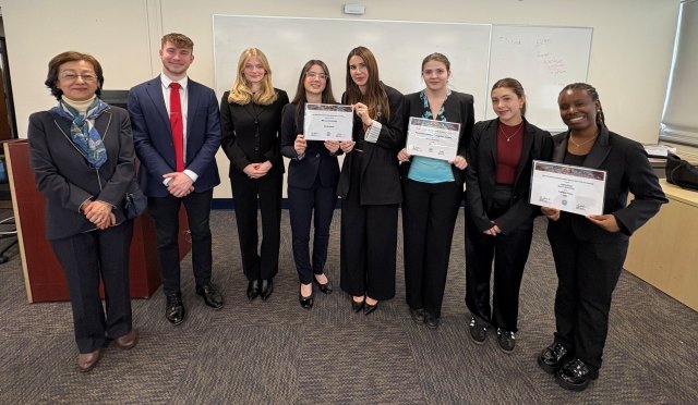 Mercy University Model UN team pose with their professor and awards from the NMUN conference in NY